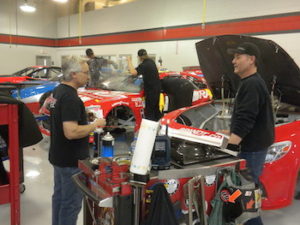 nascar team with their cars in the shop
